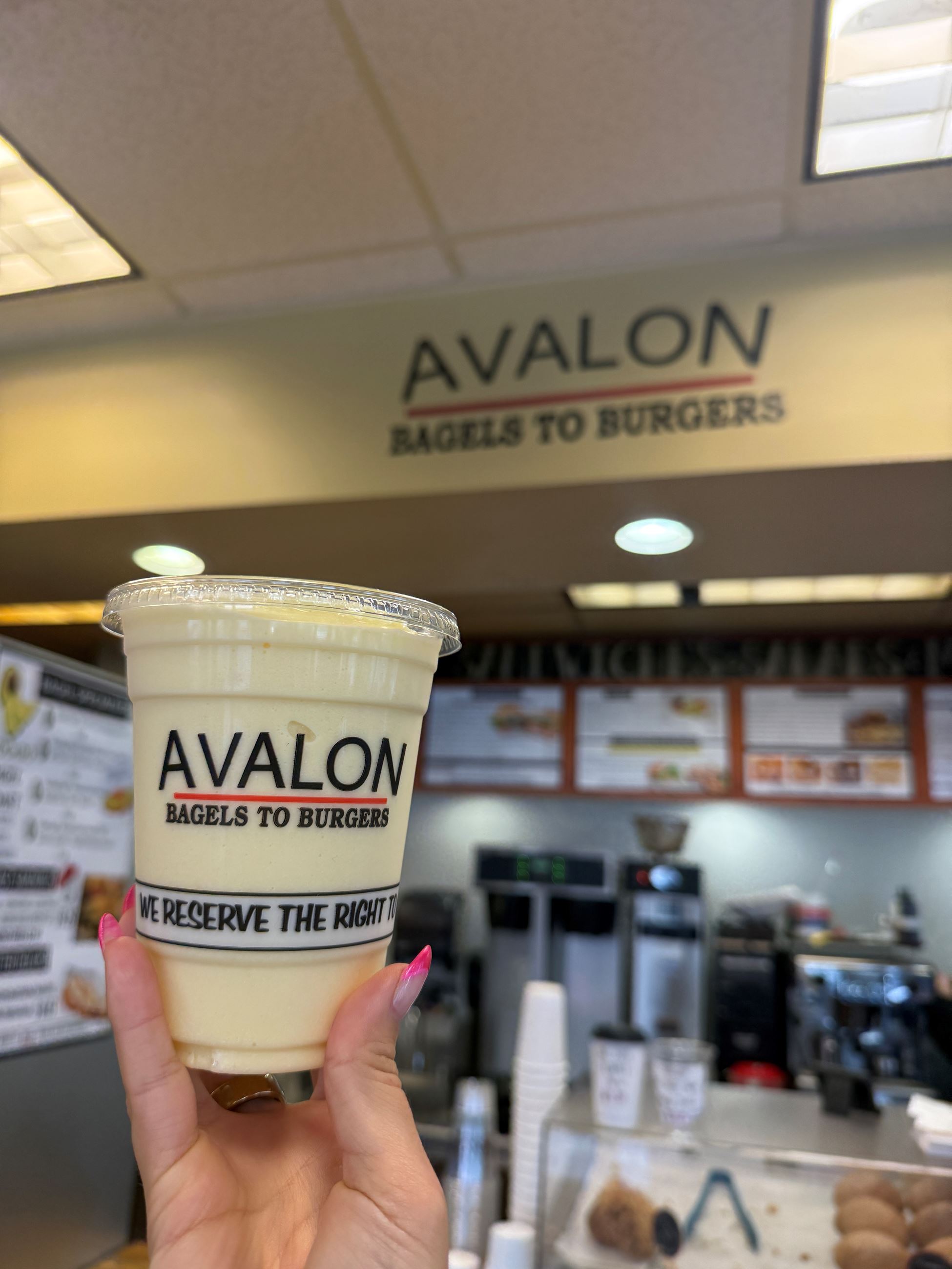 A hand holding an Avalon cup full of a creamy smoothie.